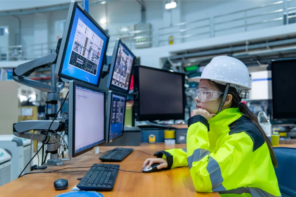 Engineer monitoring multiple screens in an industrial control room, representing AI and IoT integration for connected device management.